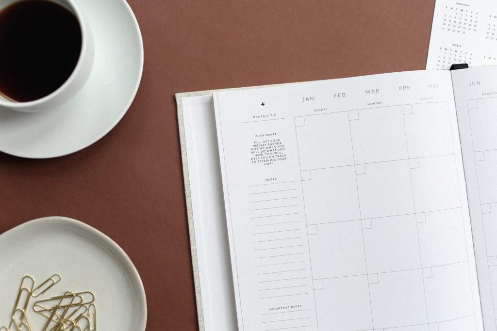 Scheduling book laying on table with coffee and paper clips